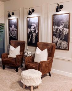 two brown chairs sitting next to each other in front of three framed pictures on the wall