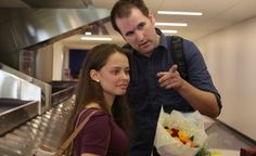 a man and woman standing next to each other in front of a counter with food on it