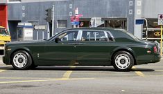 a green rolls royce parked in a parking lot