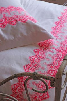 a bed with pink and white bedspread on it's side, next to two pillows