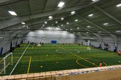 an indoor soccer field is shown with people playing in the background and on the ground