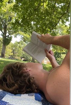 a man laying in the grass reading a book