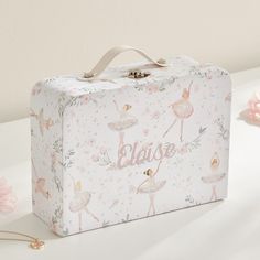 a pink and white suitcase sitting on top of a table next to some pretty flowers