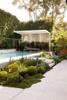 an outdoor swimming pool surrounded by plants and trees