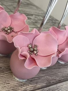 some pink flowers are sitting in small vases with silver forks sticking out of them