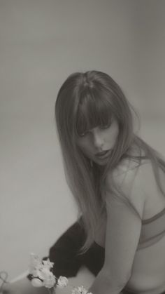 a black and white photo of a woman with long hair holding flowers in her hand