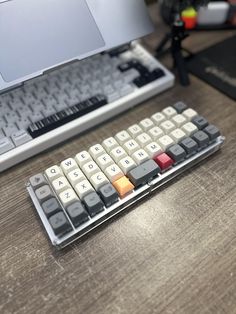 a computer keyboard sitting on top of a wooden desk next to a white laptop computer