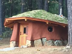 a small house in the woods with a green roof and grass on it's roof