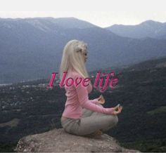 a woman sitting on top of a rock with the words i love life