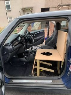 an open car door with a small table in the passenger seat and other items inside