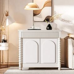 a white cabinet sitting in the middle of a living room next to a couch and lamp