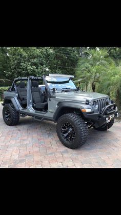 a gray jeep parked on top of a brick road