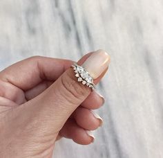 a woman's hand holding a ring with three small flowers on the middle of it