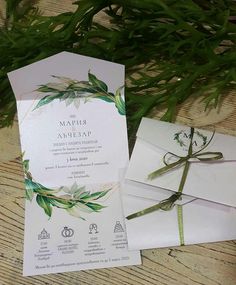 the wedding stationery is laid out next to some greenery