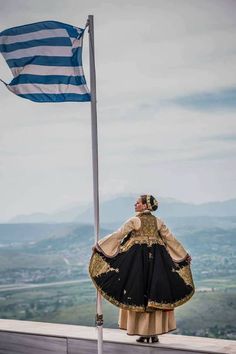 a woman standing on top of a building next to a flag