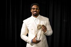 a man in a white suit holding an award