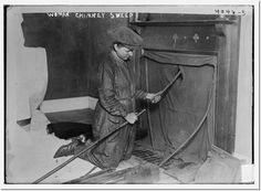 an old black and white photo of a woman cleaning a fireplace