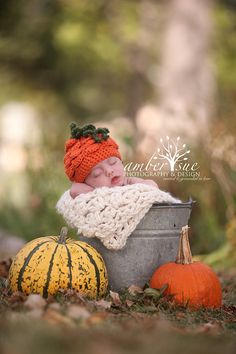 a baby in a bucket with a knitted hat and pumpkins on the ground