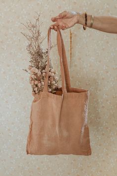 a person holding a brown bag with flowers in it and a plant hanging from the handle