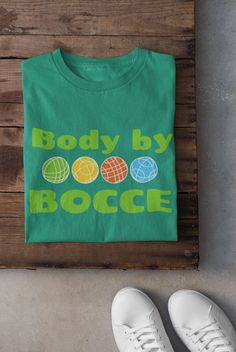 "Introducing our \"Body by Bocce\" T-shirt, a must-have for all bocce enthusiasts! This stylish and comfortable tee is perfect for showcasing your love for the popular Italian lawn game. Crafted with the finest quality materials, this shirt offers a flattering fit that will highlight your love for both fashion and bocce. Whether you're enjoying a friendly game at the park or simply relaxing with friends, this \"Body by Bocce\" T-shirt is the perfect addition to your wardrobe. Get ready to make a statement and show off your bocce skills with this unique and eye-catching tee!  You'll be the talk of the Bocce Court. .: 100% ring-spun cotton (fiber content may vary for different colors) .: Light fabric (4.5 oz/yd² (153 g/m .: Eurofit .: Tear-away label .: Runs true to size" Bocce Court, Bocce Ball, Balls Shirt, Lawn Games, Team Shirt, Team Shirts, The Park, San Jose, Adult Outfits