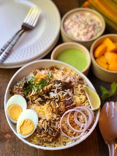 a bowl filled with rice, hard boiled eggs and other food on top of a wooden table