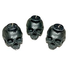 three black candles with skulls on them sitting next to each other in front of a white background