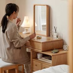 a woman sitting at a desk in front of a mirror with a lamp on it