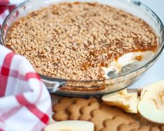 an apple pie with graham crackers on top and sliced apples in the back ground