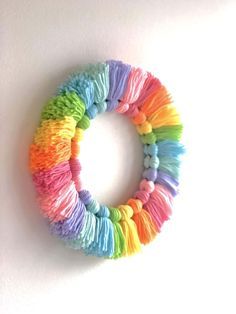 a colorful wreath made out of yarn sitting on top of a white wall