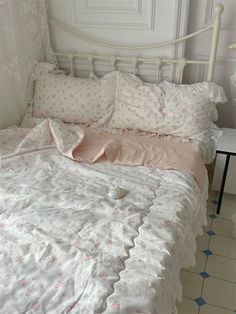 a bed with white sheets and pink pillows