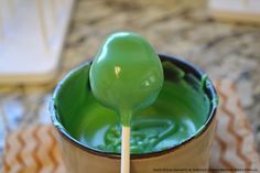 a spoon with green liquid in it on top of a cup