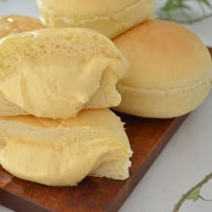 three rolls with butter spread on them sitting on a cutting board