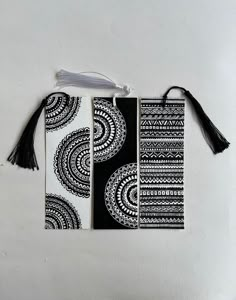 three black and white bookmarks with tassels hanging from the front, on a white background