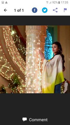 a woman standing in front of a christmas tree wearing a yellow and white shawl