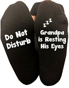 two feet wearing black socks with white words reading do not disturb grandpa is resting his eyes