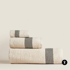 three towels stacked on top of each other in front of a white wall with black stripes