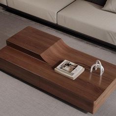 a wooden table sitting on top of a carpeted floor next to a white couch