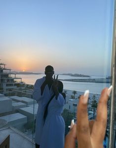 two people standing on top of a building next to each other with their fingers up in the air