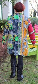 a woman standing in front of a green bench wearing black boots and a colorful coat