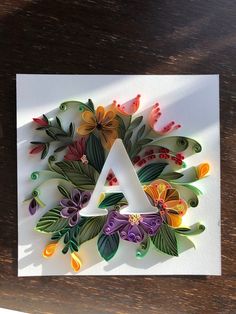 a letter made out of paper with flowers and leaves