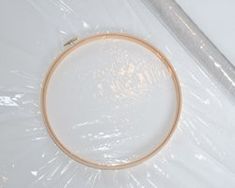 a white table with a wooden hoop on it and plastic wrap around the edges to protect it from scratches