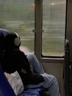 a man sitting on a bus with his headphones in his ears while holding onto another person's arm