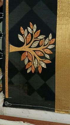 a black and gold wall hanging with a tree on it's side in front of a window