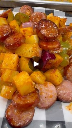 sausage, potatoes and peppers on a white plate with black and white checkered tablecloth