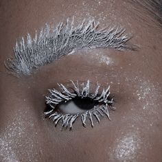 a woman's eye with white and silver makeup