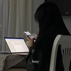 a woman sitting in front of a laptop computer on top of a white desk next to a window