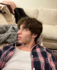 a young man sitting on top of a couch in front of a white sofa pillow