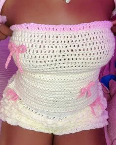 a close up of a person wearing a pink and white crochet dress with her hands on her hips