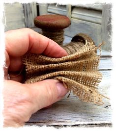 a hand holding a spool of twine next to a piece of burlock