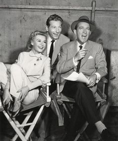 an old photo of four people sitting in folding chairs and one is holding a microphone